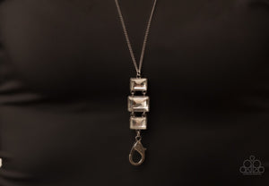 A sparkly collection of rectangular white gems stack at the bottom of a lengthened silver chain, creating a glamorous pendant. 